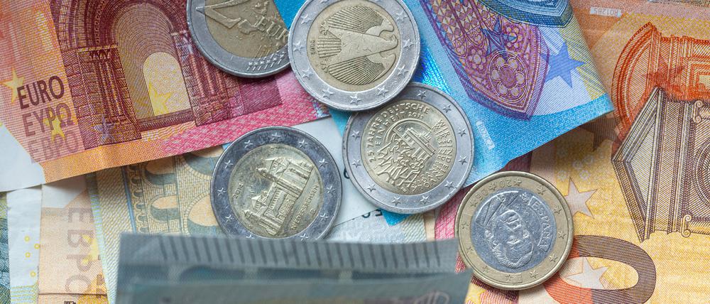 Euro-Münzen und Banknoten liegen aufeinander. (Symbolbild)