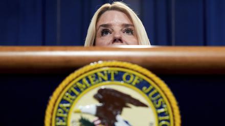Die US-Justizministerin Pam Bondi steht hinter einem Pult, auf dem das Emblem des Justizministeriums zu sehen ist. 