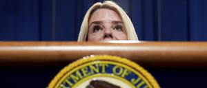Die US-Justizministerin Pam Bondi steht hinter einem Pult, auf dem das Emblem des Justizministeriums zu sehen ist. 