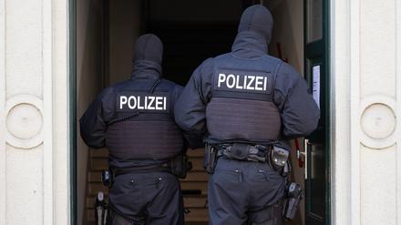  Polizisten stehen während einer Razzia in einem Hauseingang.