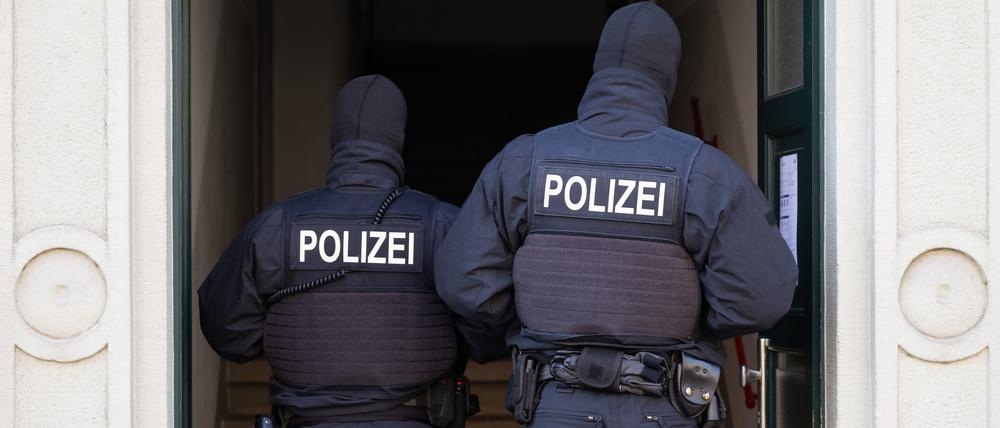Polizisten stehen während einer Razzia in einem Hauseingang.
