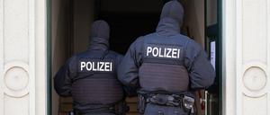  Polizisten stehen während einer Razzia in einem Hauseingang.