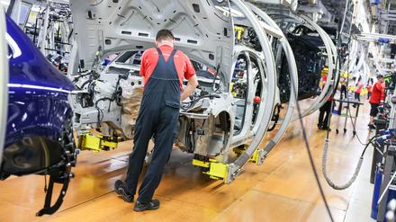 Ein Mitarbeiter in der Autoindustrie montiert Teile.