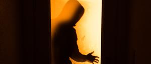 Der Schatten eines Mannes ist durch eine gläserne Tür sichtbar. (Symbolbild)