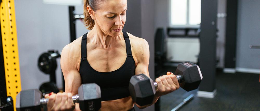 Eine Frau trainiert mit Hanteln im Fitnessstudio.