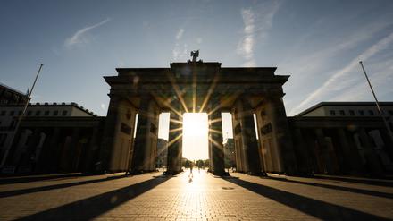 ARCHIV - 11.08.2024, Berlin: Die Sonne geht hinter dem Brandenburger Tor auf. (zu dpa: «Viel Sonne und milde Temperaturen zur neuen Woche») Foto: Christophe Gateau/dpa +++ dpa-Bildfunk +++