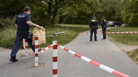 Einsatzkräfte der Polizei stehen hinter einer Absperrung an einem Weg im Stadtteil Gropiusstadt im Bezirk Neukölln, wo ein Polizist am frühen Morgen einen toten Säugling gefunden hat. 