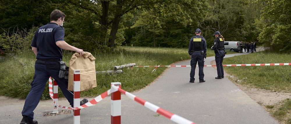 Einsatzkräfte der Polizei stehen hinter einer Absperrung an einem Weg im Stadtteil Gropiusstadt im Bezirk Neukölln, wo ein Polizist am frühen Morgen einen toten Säugling gefunden hat. 