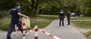 Einsatzkräfte der Polizei stehen hinter einer Absperrung an einem Weg im Stadtteil Gropiusstadt im Bezirk Neukölln, wo ein Polizist am frühen Morgen einen toten Säugling gefunden hat.