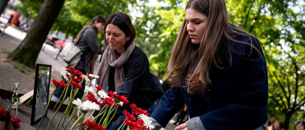 Menschen legen bei der Gedenkveranstaltung zu Çetin Merts Tod vor 50 Jahren Blumen vor die Gedenktafel.
