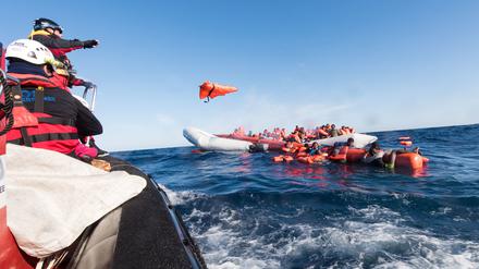 Archiv: Mitarbeiter der Hilfsinitiative SOS Mediterranee werfen Geflüchteten im Mittelmeer vor der libyschen Küste Rettungswesten zu.