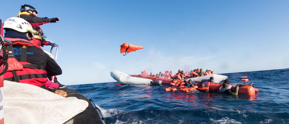 Archiv: Mitarbeiter der Hilfsinitiative SOS Mediterranee werfen Geflüchteten im Mittelmeer vor der libyschen Küste Rettungswesten zu.