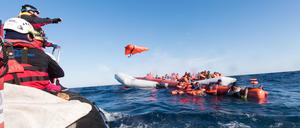 Archiv: Mitarbeiter der Hilfsinitiative SOS Mediterranee werfen Geflüchteten im Mittelmeer vor der libyschen Küste Rettungswesten zu.