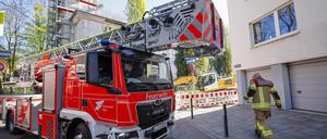 Ein Drehleiterfahrzeug der Feuerwehr wird von einem Feuerwehrmann in einer engen Straße eingewiesen. (Symbolbild)