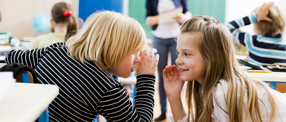 Girl and boy whispering in calssroom