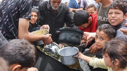 Palästinensische Kinder drängeln, um eine Ration Essen zu bekommen. Diese wurden von einer Wohltätigkeits-Küche auf dem Campus der Islamischen Universität in Gaza am 12. Mai 2025 ausgegeben.