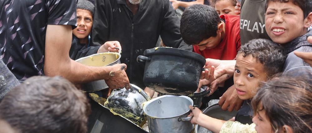 Palästinensische Kinder drängeln, um eine Ration Essen zu bekommen. Diese wurden von einer Wohltätigkeits-Küche auf dem Campus der Islamischen Universität in Gaza am 12. Mai 2025 ausgegeben.