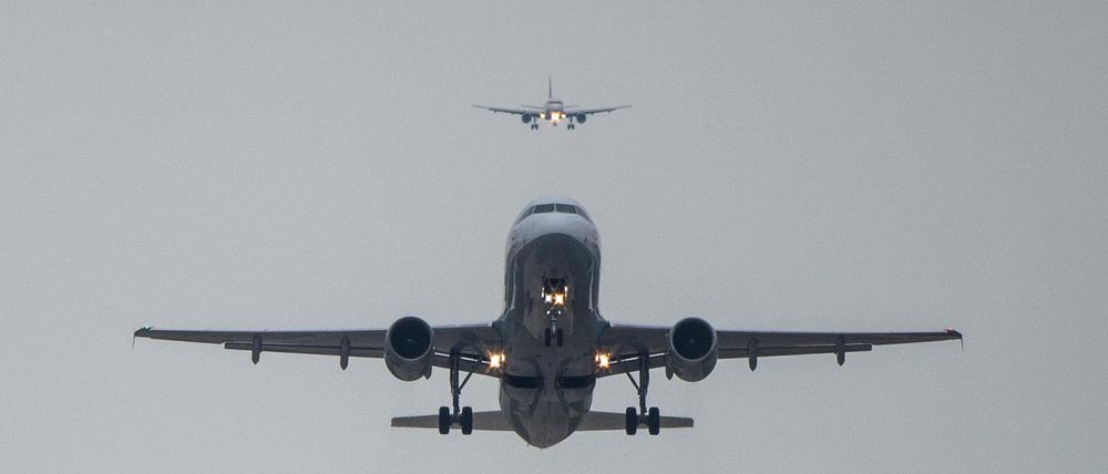 Ein Airbus 320 startet während dahinter ein Airbus 319  im Landeanflug ist. 