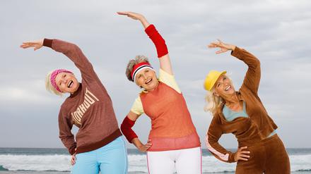 Three senior women stretching on beach