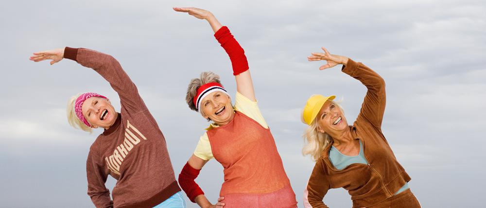 Three senior women stretching on beach