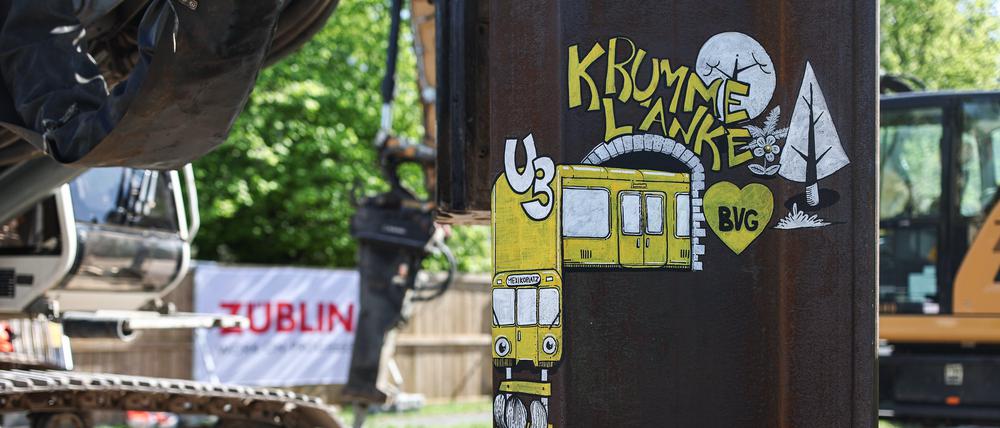 Auf einer Spundwand ist eine U-Bahn mit dem Schriftzug „Krumme Lanke“ und „Mexikoplatz“ gezeichnet. Durch eine Direktverbindung sollen die zwei Bahnhöfe Mexikoplatz und Krumme Lanke verbunden werden.