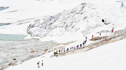 Touristen auf dem Weg zur künstlich ins Eis gehauenen Gletschergrotte, Rhonegletscher, Schweiz, 2019