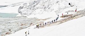 Touristen auf dem Weg zur künstlich ins Eis gehauenen Gletschergrotte, Rhonegletscher, Schweiz, 2019
