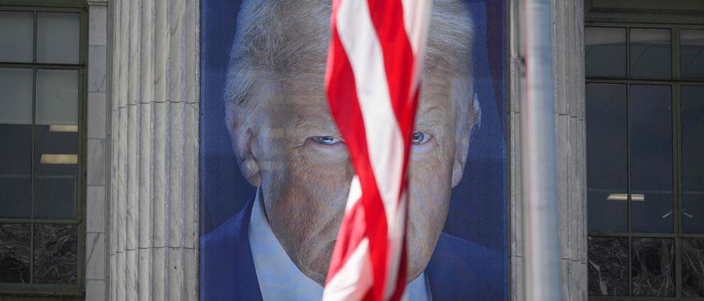 Ein US-Flagge vor einem Gebäude mit einem Konterfei von Donald Trump in Washington.