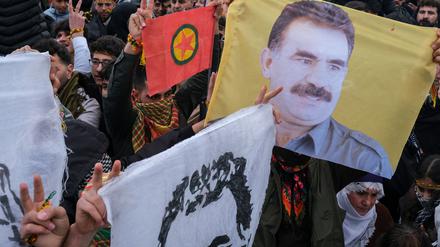 21.03.2025, Türkei, Diyarbakir: Junge Kurden halten ein Plakat des inhaftierten Anführers der militanten PKK, Abdullah Öcalan. 