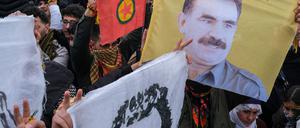 21.03.2025, Türkei, Diyarbakir: Junge Kurden halten ein Plakat des inhaftierten Anführers der militanten PKK, Abdullah Öcalan. 