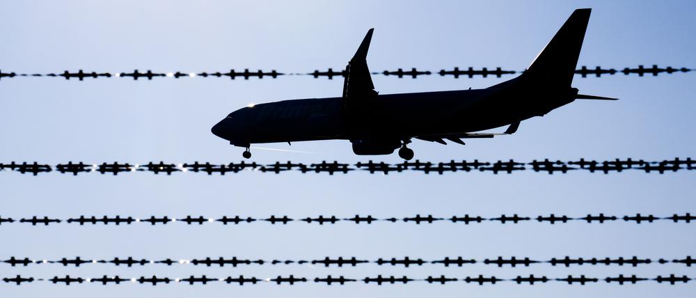 Ein Flugzeug fliegt hinter Stacheldraht am Flughafen Hannover.