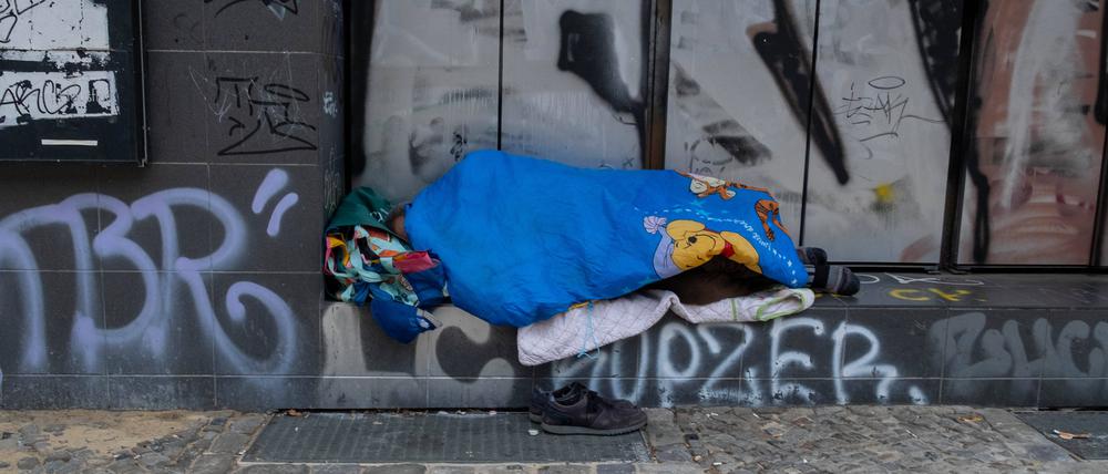 Ein Obdachloser schlaft vor einem geschlossenen Geschäft in Berlin.