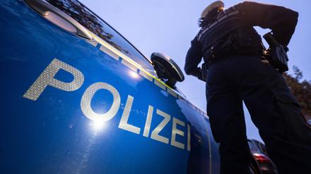 Eine Polizistin steht neben einem Polizeifahrzeug.
