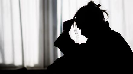 19.02.2025, Niedersachsen, Hannover: ILLUSTRATION - Die Silhouette einer Frau zeichnet sich vor einer hellen Fensterfront ab (gestellte Szene). 
