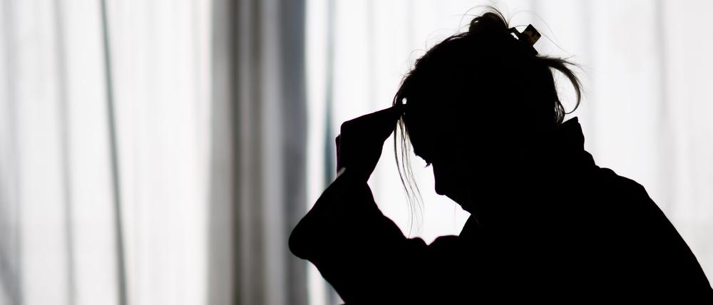19.02.2025, Niedersachsen, Hannover: ILLUSTRATION - Die Silhouette einer Frau zeichnet sich vor einer hellen Fensterfront ab (gestellte Szene).