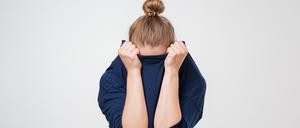 Eine Frau zieht sich beschämt ihren Pullover übers Gesicht.