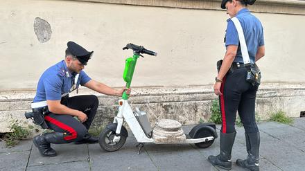 Zwei Carabinieri begutachten den Marmorsockel auf einem elektrischen Leihroller.