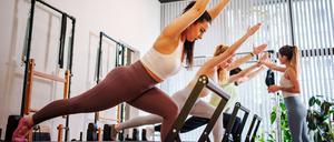 Drei Frauen trainieren mit einer Trainerin in einem Pilates-Studio.