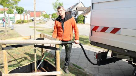 Michael Schmidt vom Betriebshof der Stadt Wittenberge (Landkreis Prignitz) gießt einen Baum in einer Straße nahe der Innenstadt. 