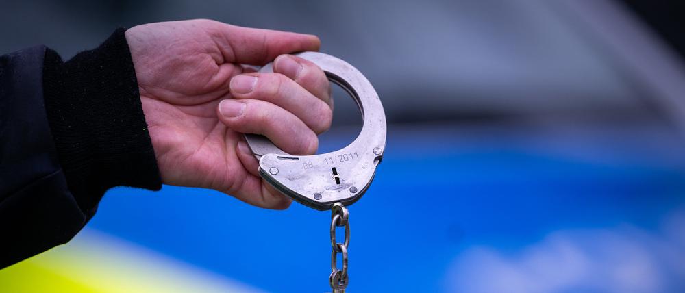 Ein Polizist hält während einer Verkehrskontrolle an der Berliner Straße ein Paar Handschellen.