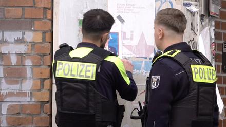Zwei Polizisten entfernen ein Plakat, das den am Mittwoch erschossenen Deutsch-Israeli Yaron Lischinsky zeigt.