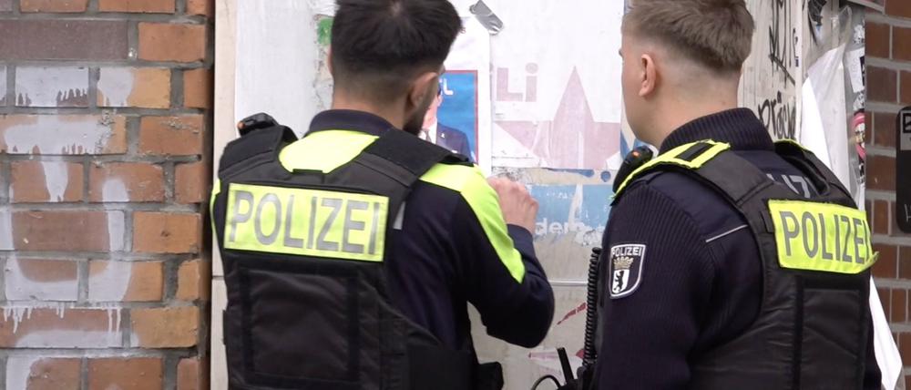 Zwei Polizisten entfernen ein Plakat, das den am Mittwoch erschossenen Deutsch-Israeli Yaron Lischinsky zeigt.