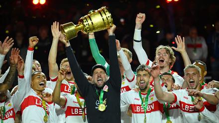 Der Trainer hält den Pokal in die Luft.
