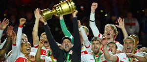 Der Trainer hält den Pokal in die Luft.