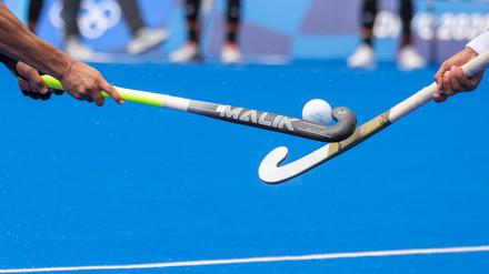 Zwei Spieler kämpfen mit den Hockeyschlägern um den Ball.