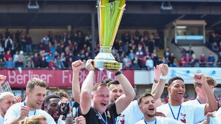 Trainer Dennis Kutrieb feiert mit seinen Spielern den Pokal.