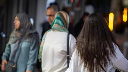 Eine Frau läuft in Teheran mit offenen Haaren am Abend eine Straße entlang (Symbolbild).