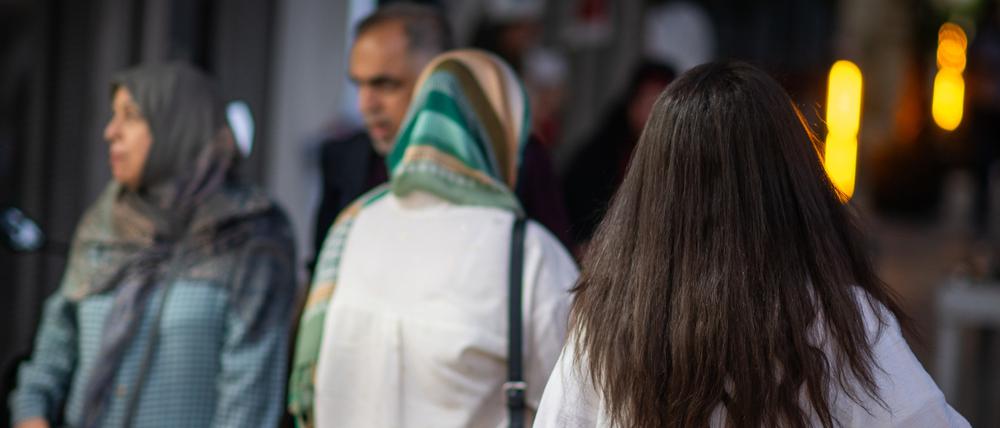 Eine Frau läuft in Teheran mit offenen Haaren am Abend eine Straße entlang (Symbolbild).