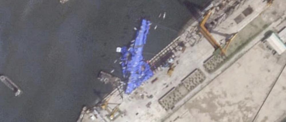 Dieses Satellitenbild von Planet Labs PBC zeigt eine blaue Plane, die einen nordkoreanischen Zerstörer abdeckt, der noch während der Einweihungszeremonie stark beschädigt wurde.