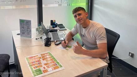 Max Erdne sitzt an einem Schreibtisch bei seinem Ausbildungsbetrieb Elixia Vitalclub in Lichterfelde.